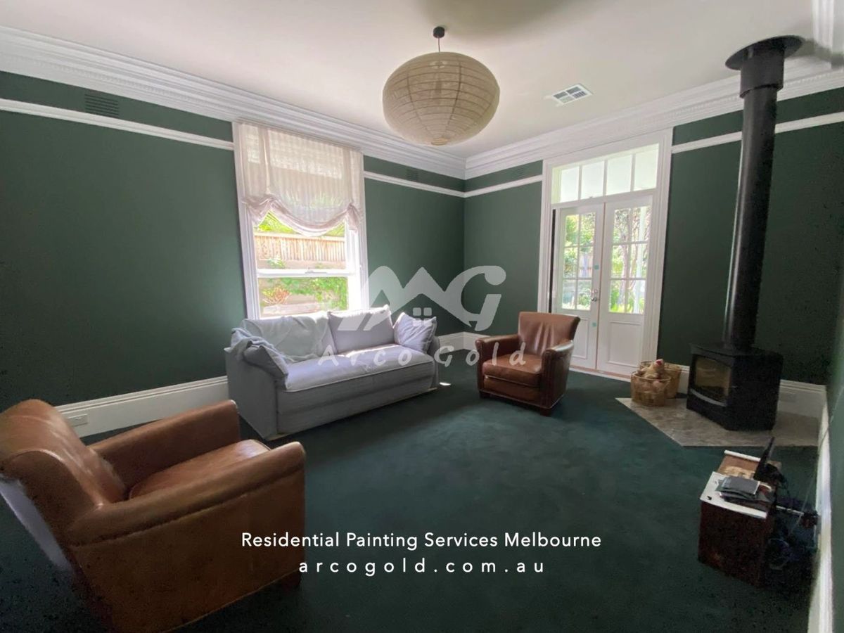 Deep green living room with white cornices and a wood fireplace